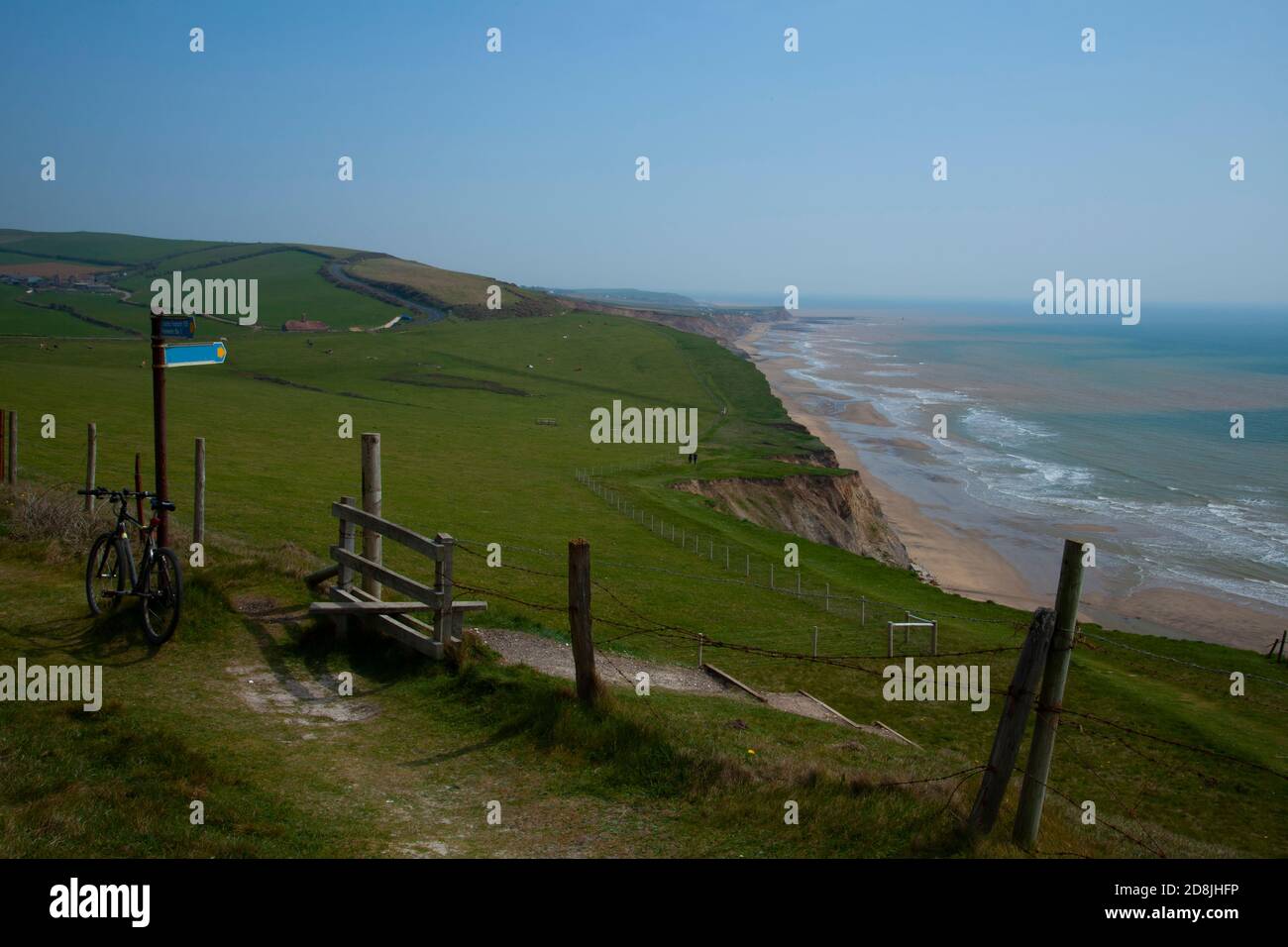 Vista panoramica sulla costa dell'Isola di Wight con l'oceano, una spiaggia stretta ai piedi delle scogliere. Un prato verde è sulla cima delle scogliere con strada Foto Stock