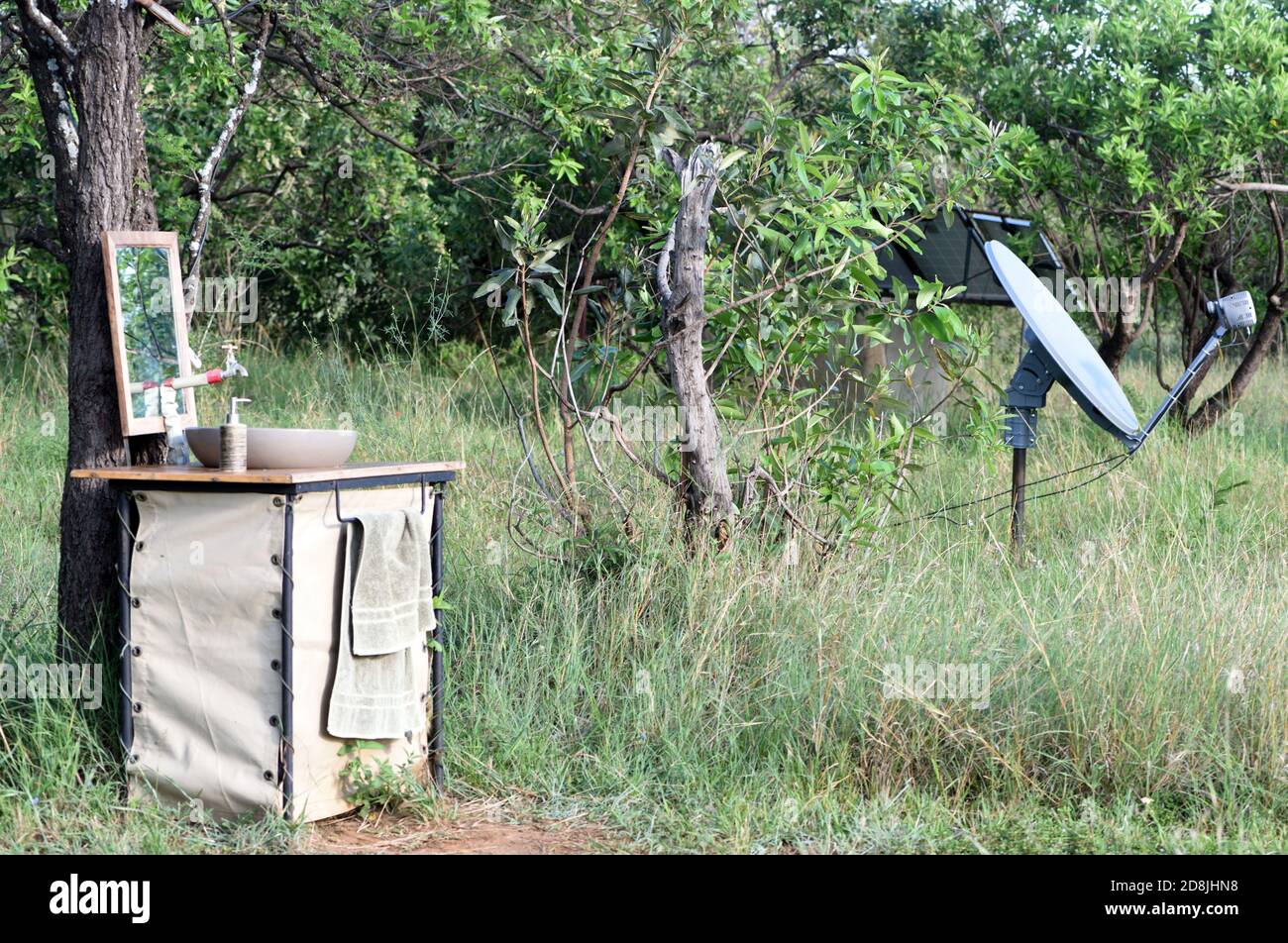 Un lavatoio e una parabola portatile per telecomunicazioni sul bordo di un campo safari. Parco Nazionale di Serengeti, Tanzania. Foto Stock