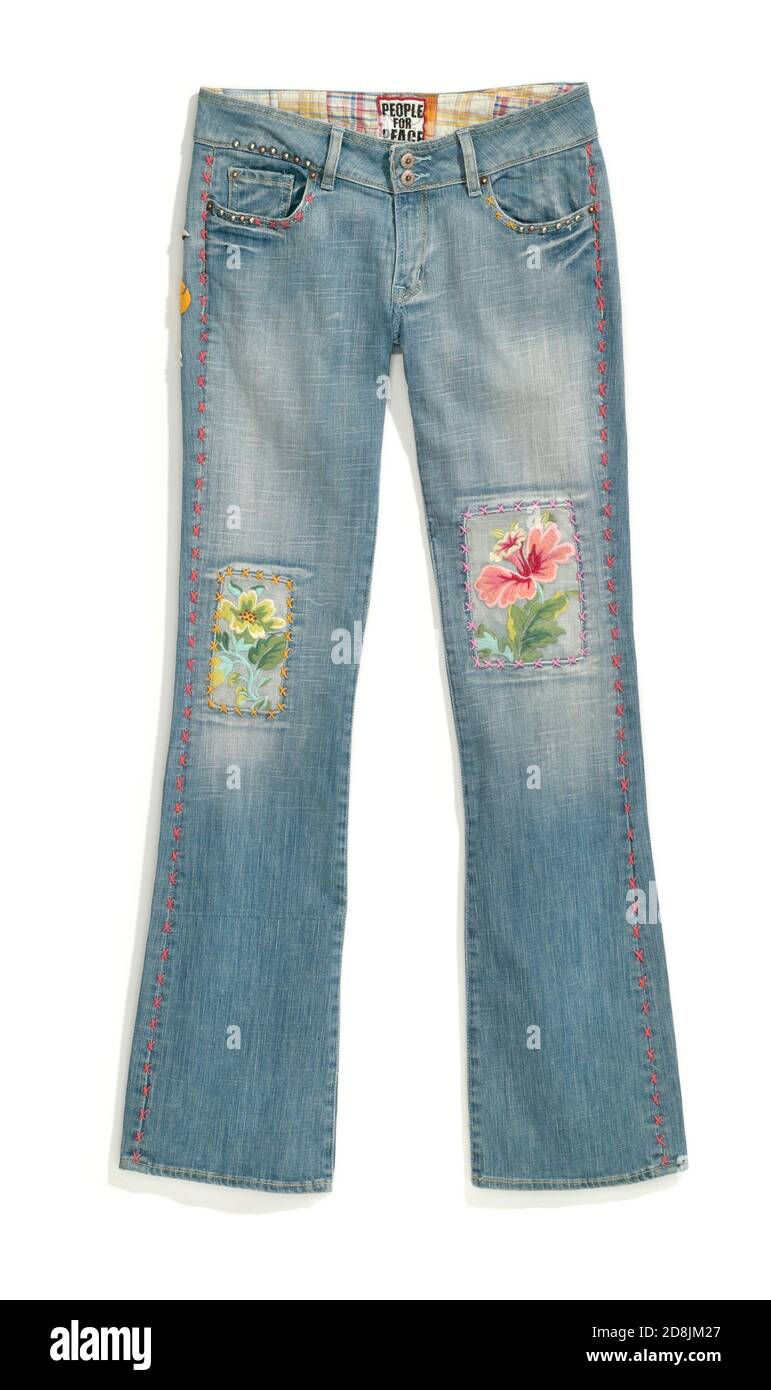 Jeans pappagallo sbiaditi con chiazze di ginocchio di fiori ricamate fotografate sopra uno sfondo bianco Foto Stock