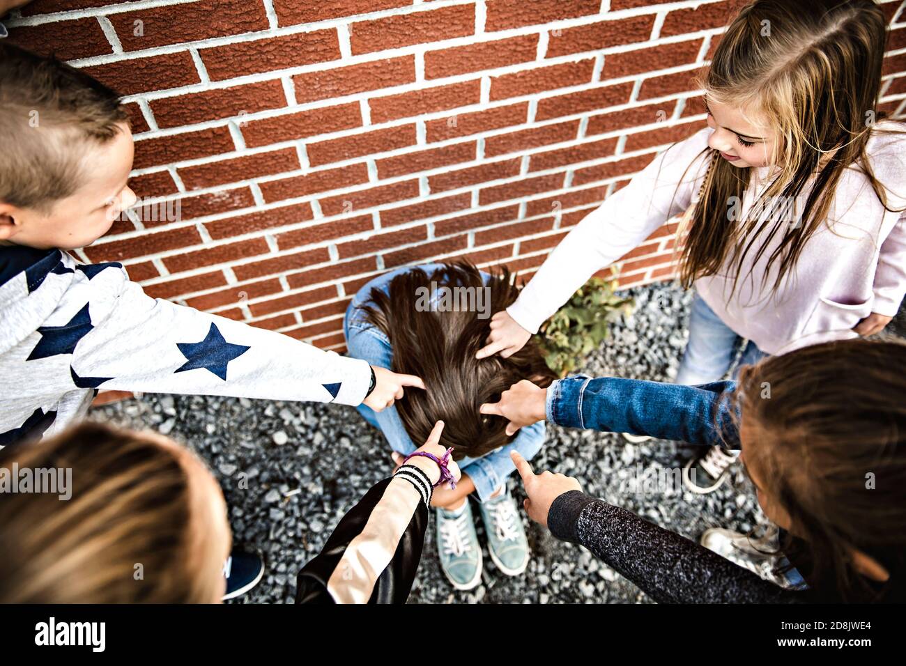 Triste momento di intimidazione. La ragazza siede sul terreno bullendo in cortile scolastico Foto Stock