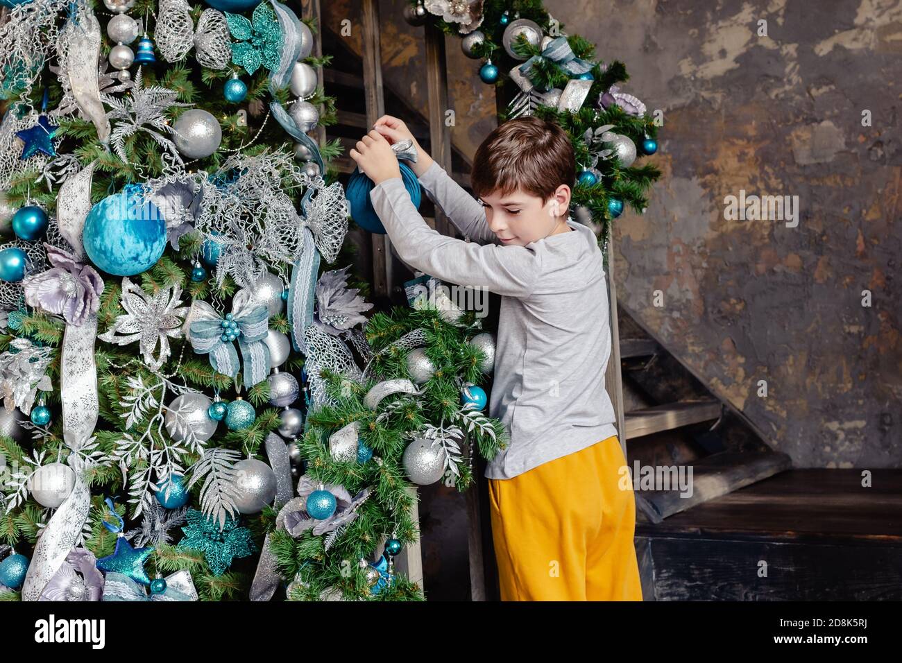 Ragazzo piccolo che decorano l'albero di Natale con le palle blu in soggiorno per Natale. Buon Natale e buon Natale concetto. Foto Stock