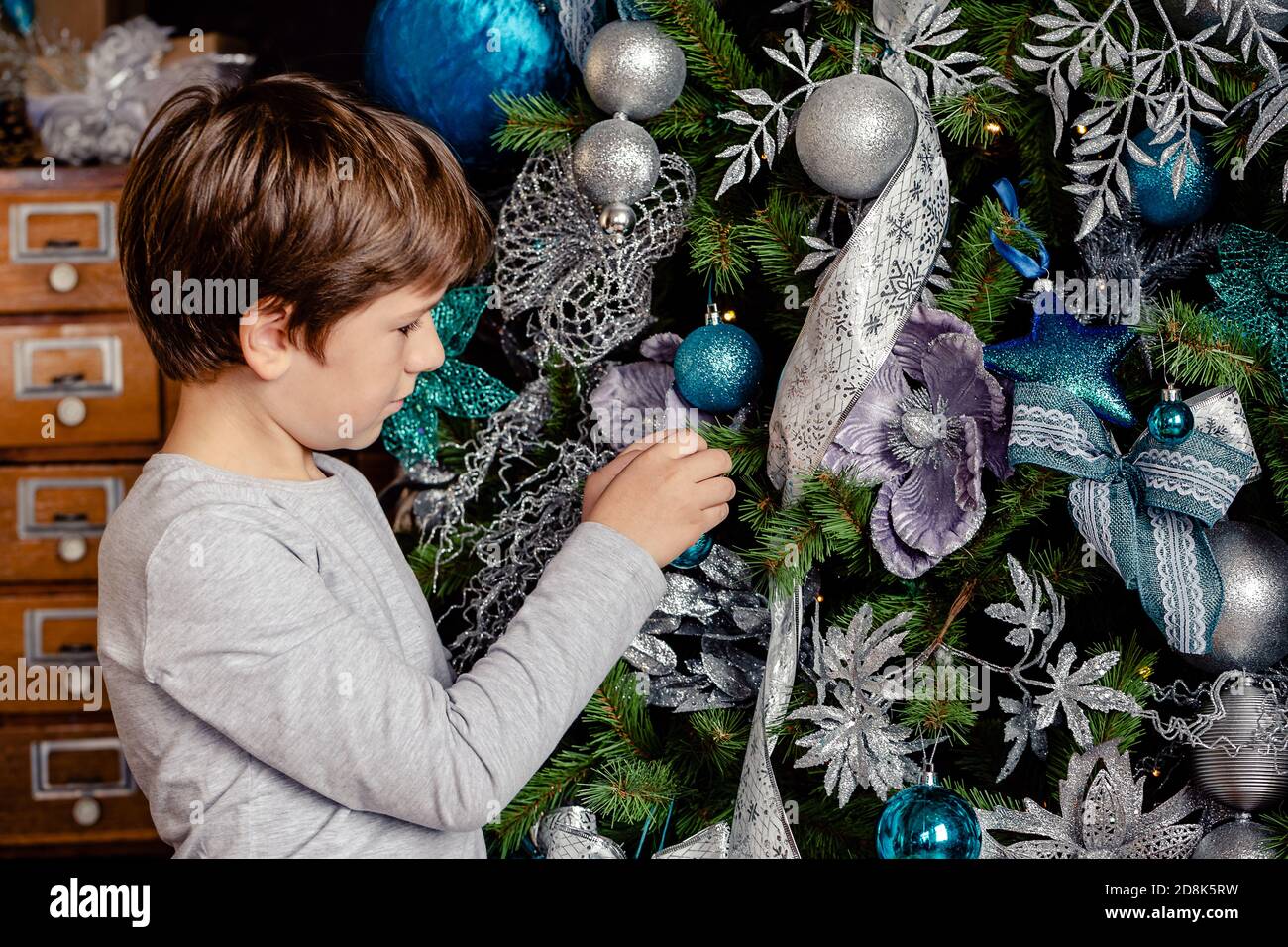 Ragazzo piccolo che decorano l'albero di Natale con le palle blu in soggiorno per Natale. Buon Natale e buon Natale concetto. Foto Stock