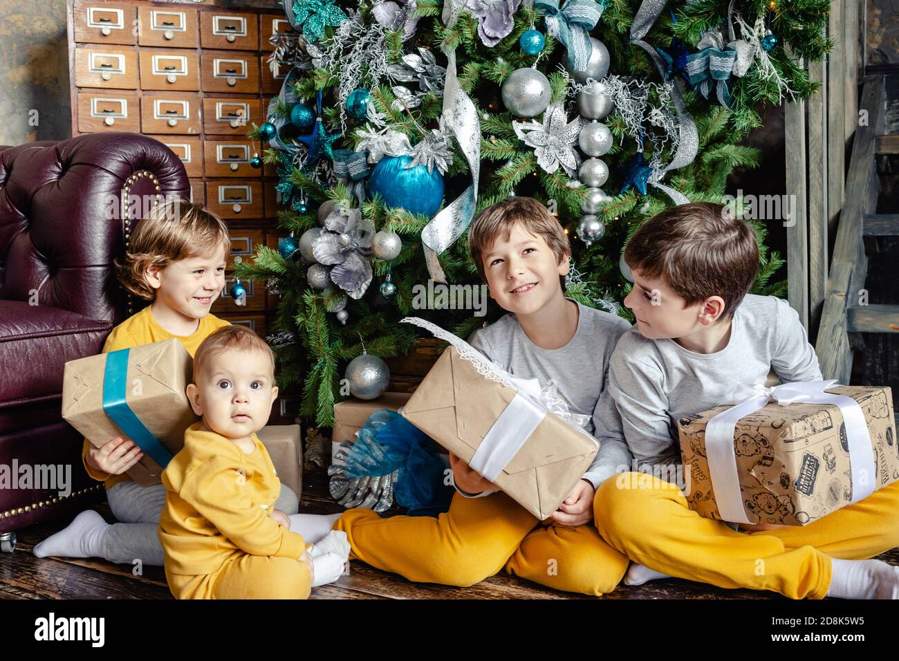 Felici i fratelli bambini che aprono i regali davanti all'albero di Natale.  Tempo di Natale. Concentratevi sul bambino Foto stock - Alamy