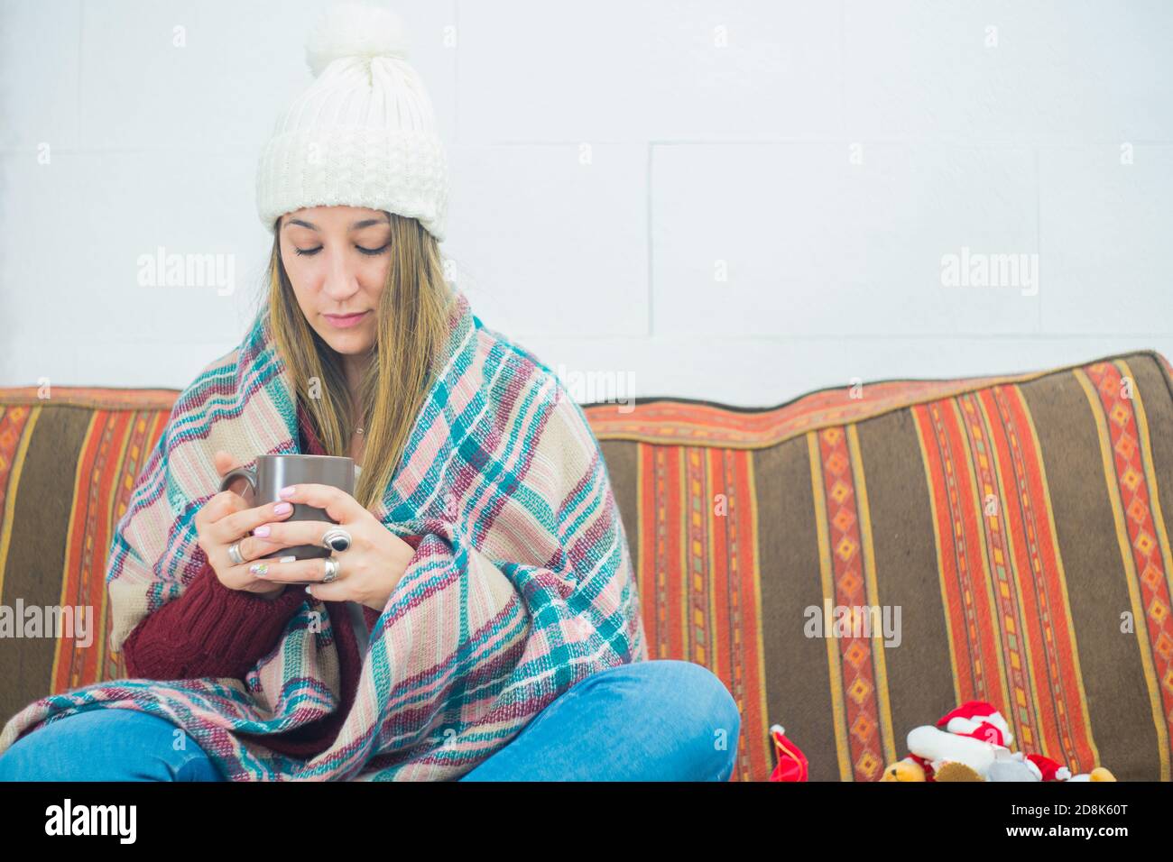 Primo piano di una ragazza coperta con una sciarpa una tazza sul divano Foto Stock