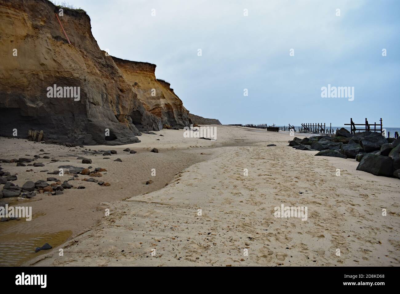 Le scogliere di Happisburgh Beach che mostrano erosione costiera, Norfolk, Regno Unito. Le antiche difese marine in legno sono visibili lungo il bordo della spiaggia. Foto Stock