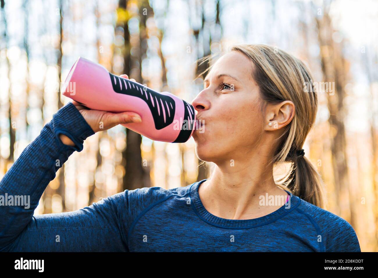 Una giovane donna che beve acqua dopo l'esercizio fisico Foto Stock