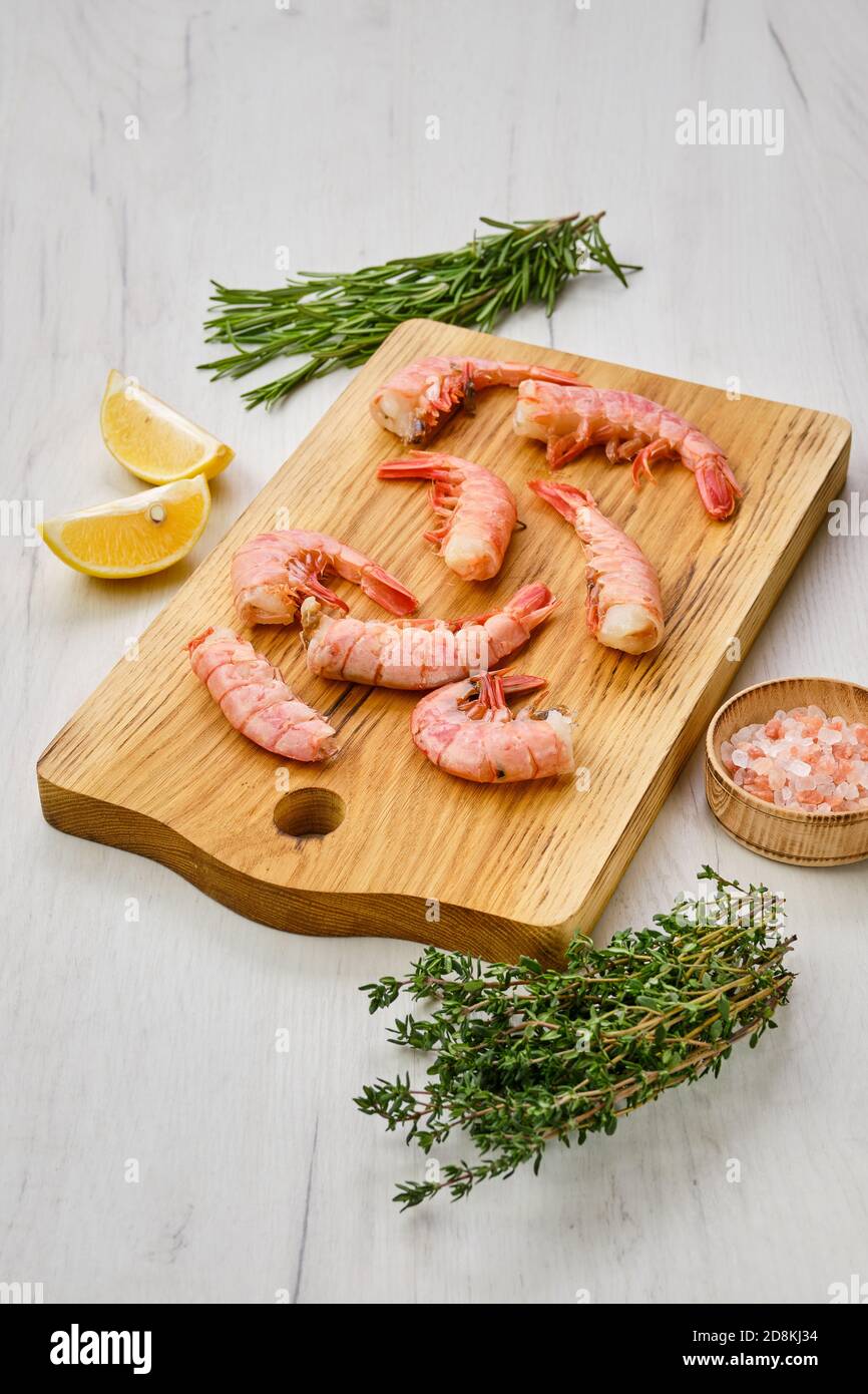 Code di gamberetti surgelate surgelate su tagliere di legno Foto Stock