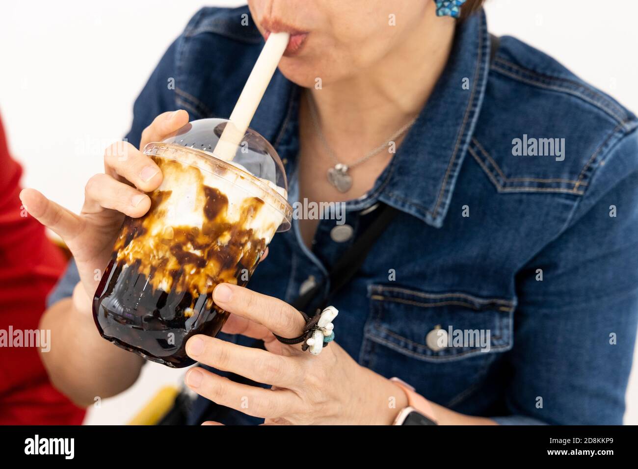 Donna che gode il suo bicchiere di caramello bolla tè boba Foto Stock