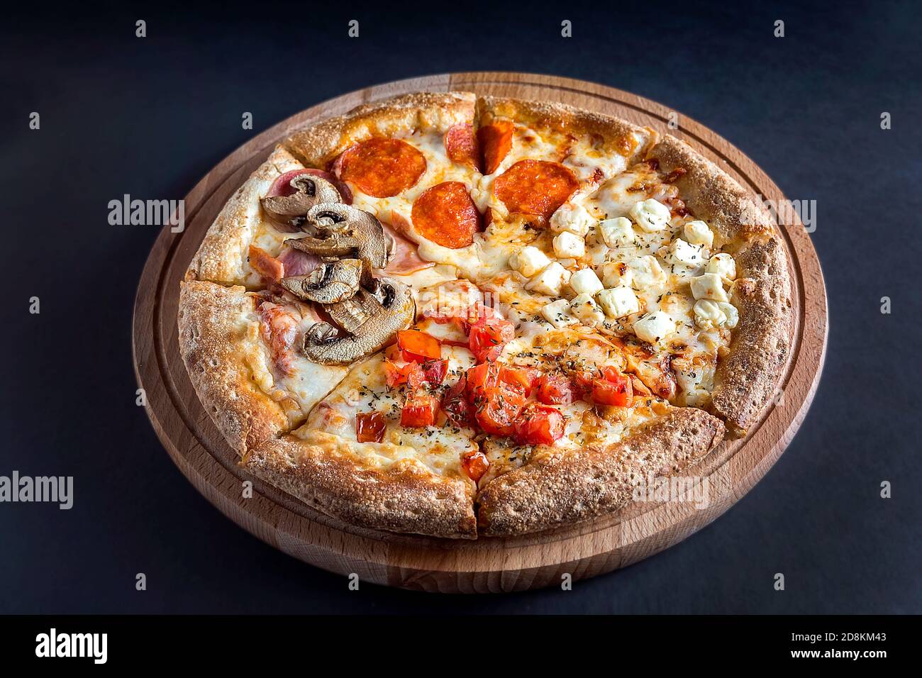 La pizza giace su un tagliere di legno su uno sfondo scuro.quattro gusti  diversi di pizza. Spazio per il testo. La vista dall'alto Foto stock - Alamy