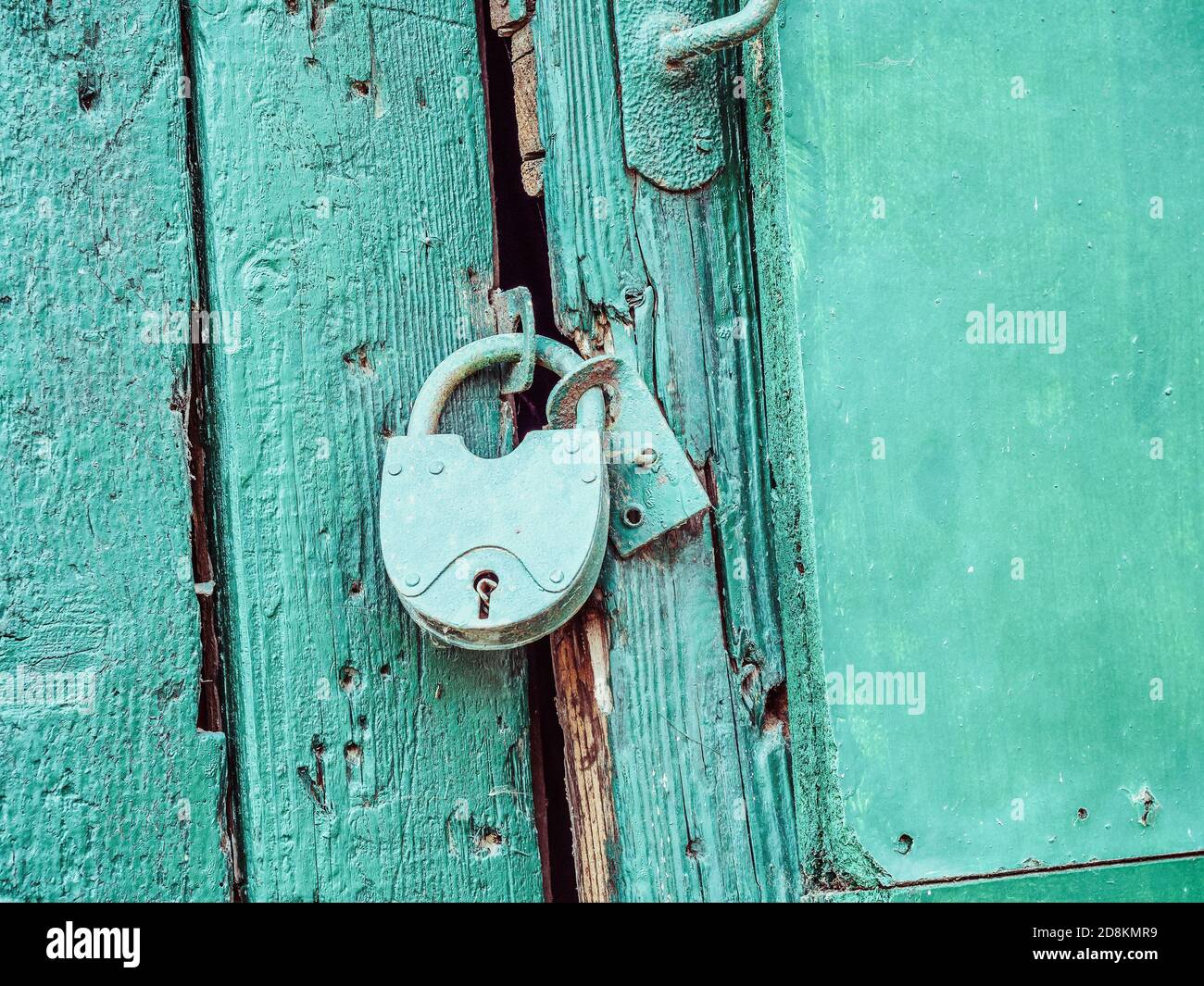 Una serratura di ferro blu pende su una vecchia porta di legno blu. Foto di primo piano Foto Stock