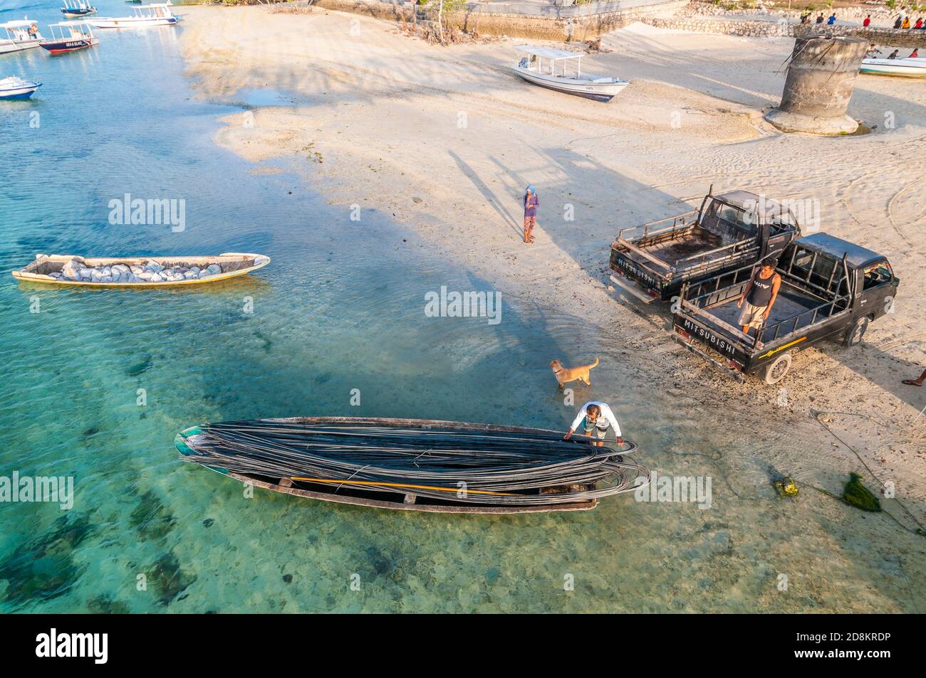 I lavoratori manuali scaricano aste di acciaio da una barca, Lembongan, Bali, Indonesia Foto Stock
