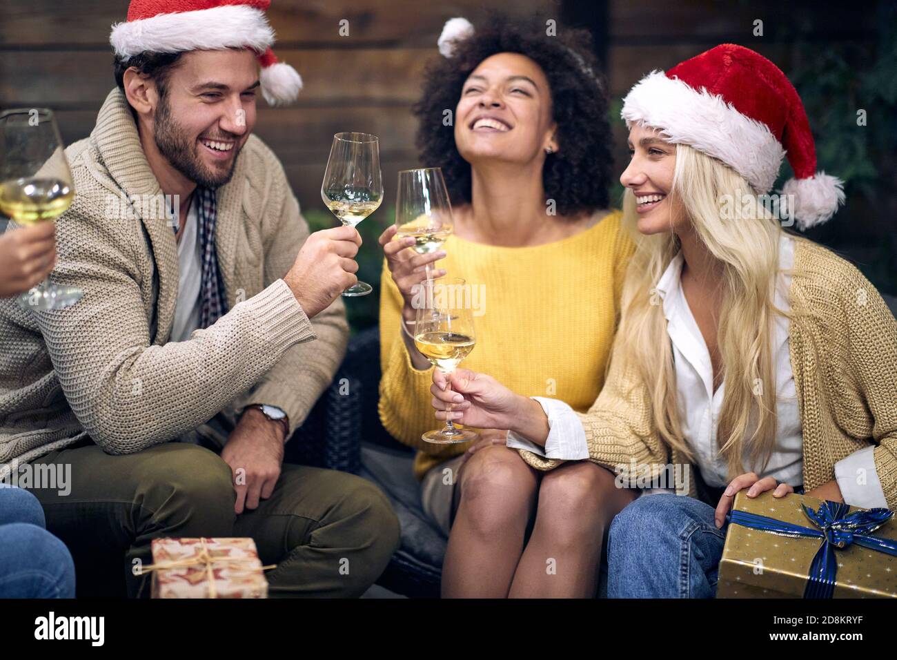 Gruppo di giovani allegri che gustano champagne in un'atmosfera festosa a natale o a festa di Capodanno insieme. Natale, amici, toast, divertimento, party conc Foto Stock