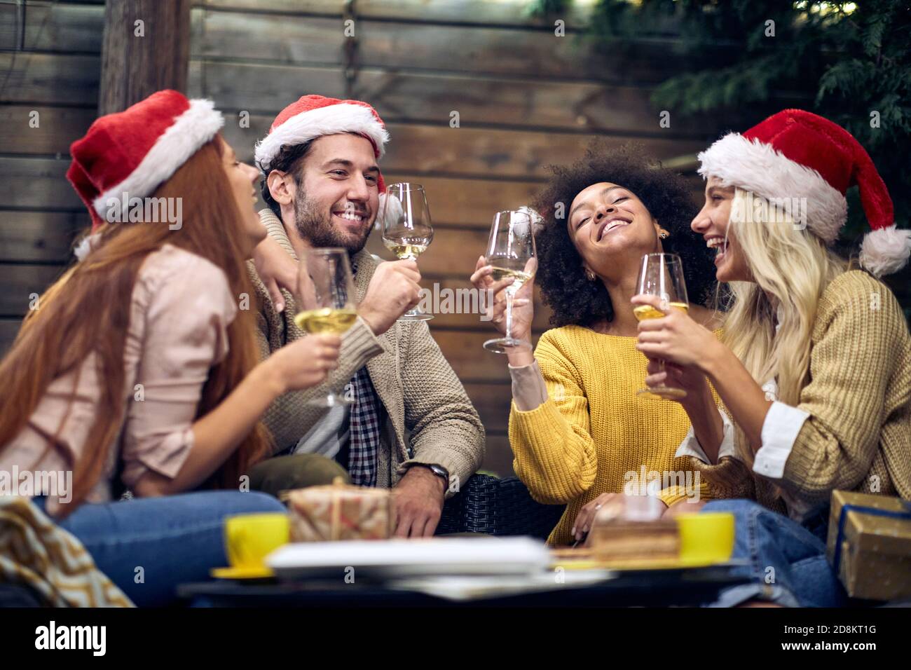 Gruppo di giovani allegri persone che chiacchierano e bevono a natale o festa di Capodanno in un'atmosfera di festa insieme. Natale, amici, toast, divertimento, festa c Foto Stock