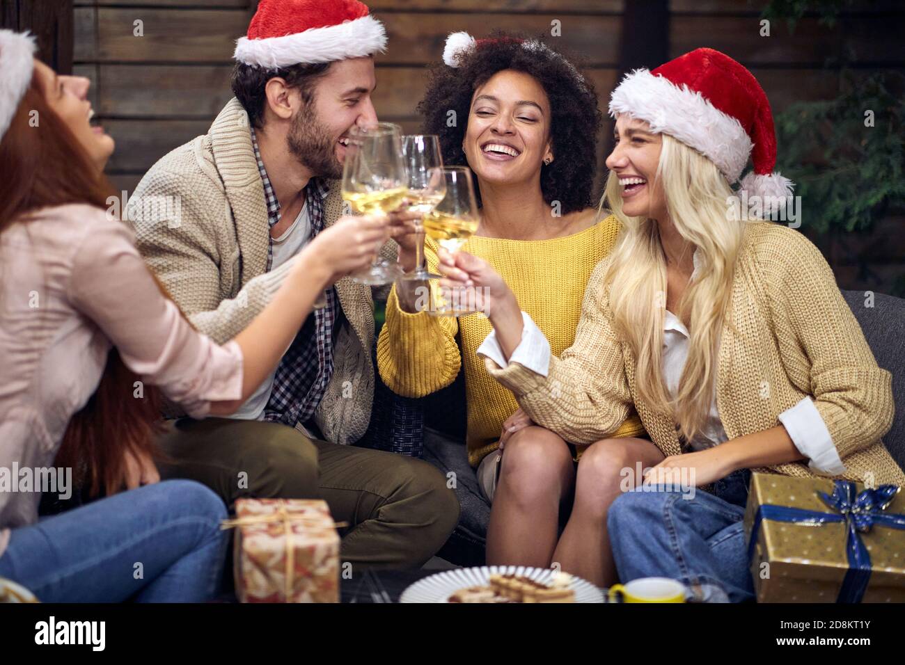 Gruppo di giovani allegri festeggiamenti per natale o festa di Capodanno bevendo champagne in un'atmosfera festosa insieme. Natale, amici, toast, divertimento, p Foto Stock