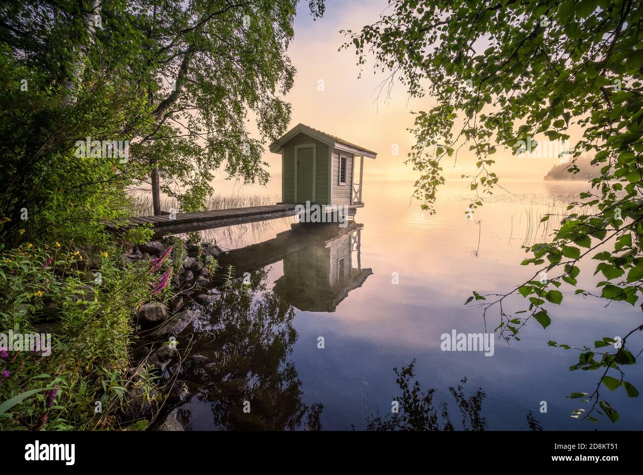 Splendido paesaggio mattutino con un piccolo cottage per nuotare, un molo e un'alba in riva al lago in Finlandia Foto Stock