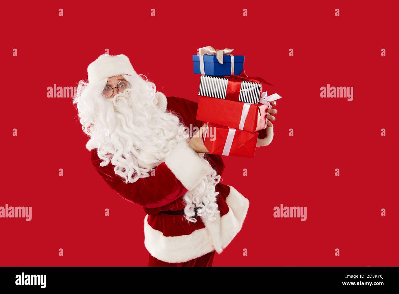 Felice Babbo Natale che tiene scatole con regali su un rosso sfondo Foto Stock