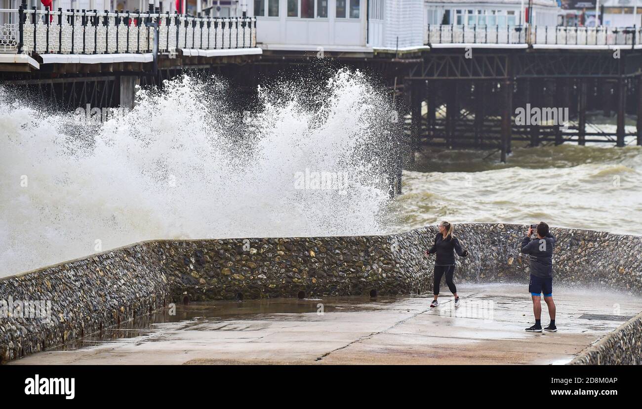 Brighton UK 31 ottobre 2020 - UNA coppia ottiene uno sguardo ravvicinato alle onde che si infrangono sul lungomare di Brighton come Storm Aiden colpisce parti della Gran Bretagna con avvertimenti di grandi venti e possibili danni alla proprietà: Credit Simon Dack / Alamy Live News Foto Stock