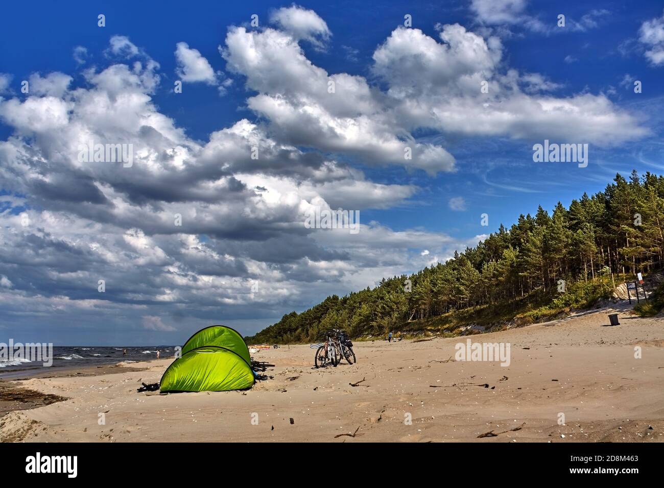 Biciclette parcheggiate presso la tenda verde su una spiaggia di mare in estate. Foto Stock