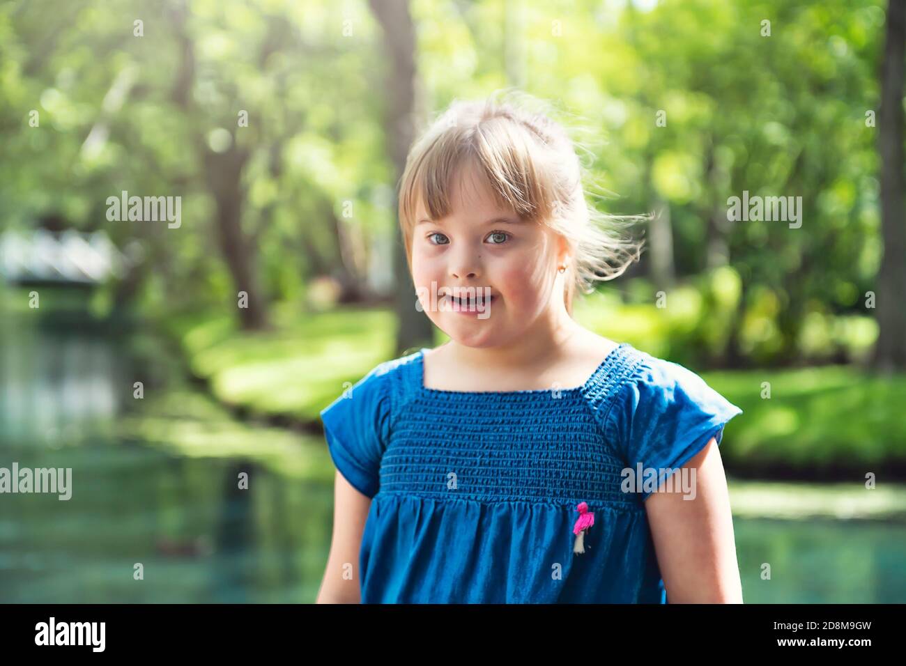 Un ritratto di trisomie 21 bambina ragazza fuori divertirsi su un parco Foto Stock