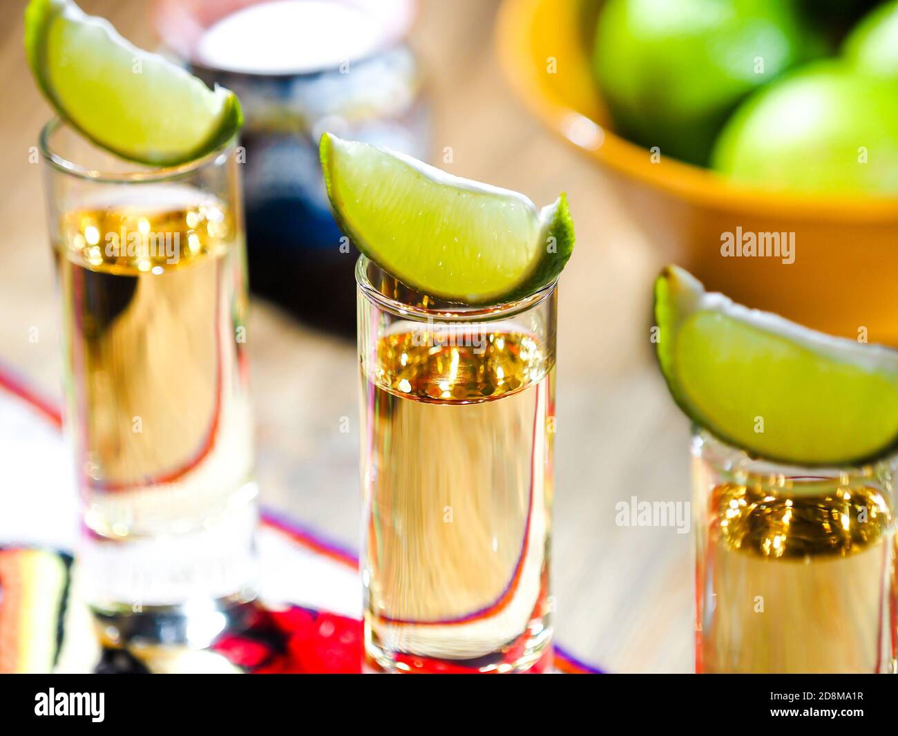 Tre tiri di tequila in alti bicchieri con lime cunei sulla parte superiore Foto Stock