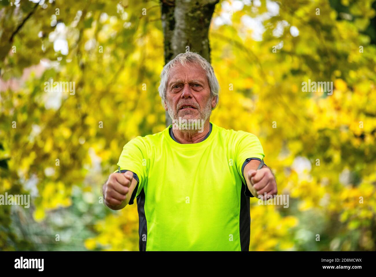 Un uomo alla fine degli anni sessanta si esercita all'aperto con una banda di resistenza in autunno. Foto Stock