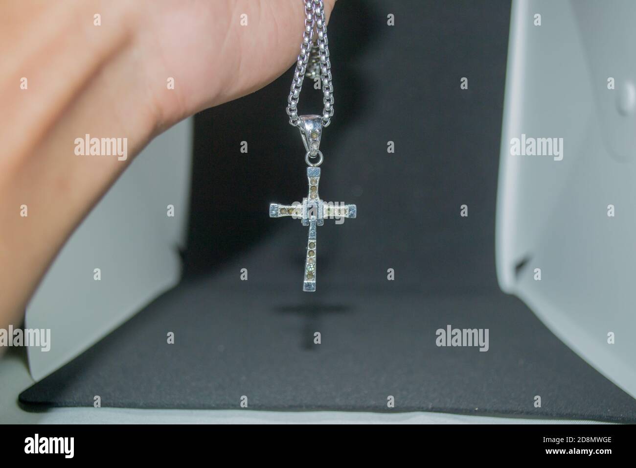 Immagine ravvicinata di una collana/pendente a croce cristiana in metallo argento o. collana/pendente in metallo-argento con crocifisso appeso su un bianco e nero sfondo Foto Stock