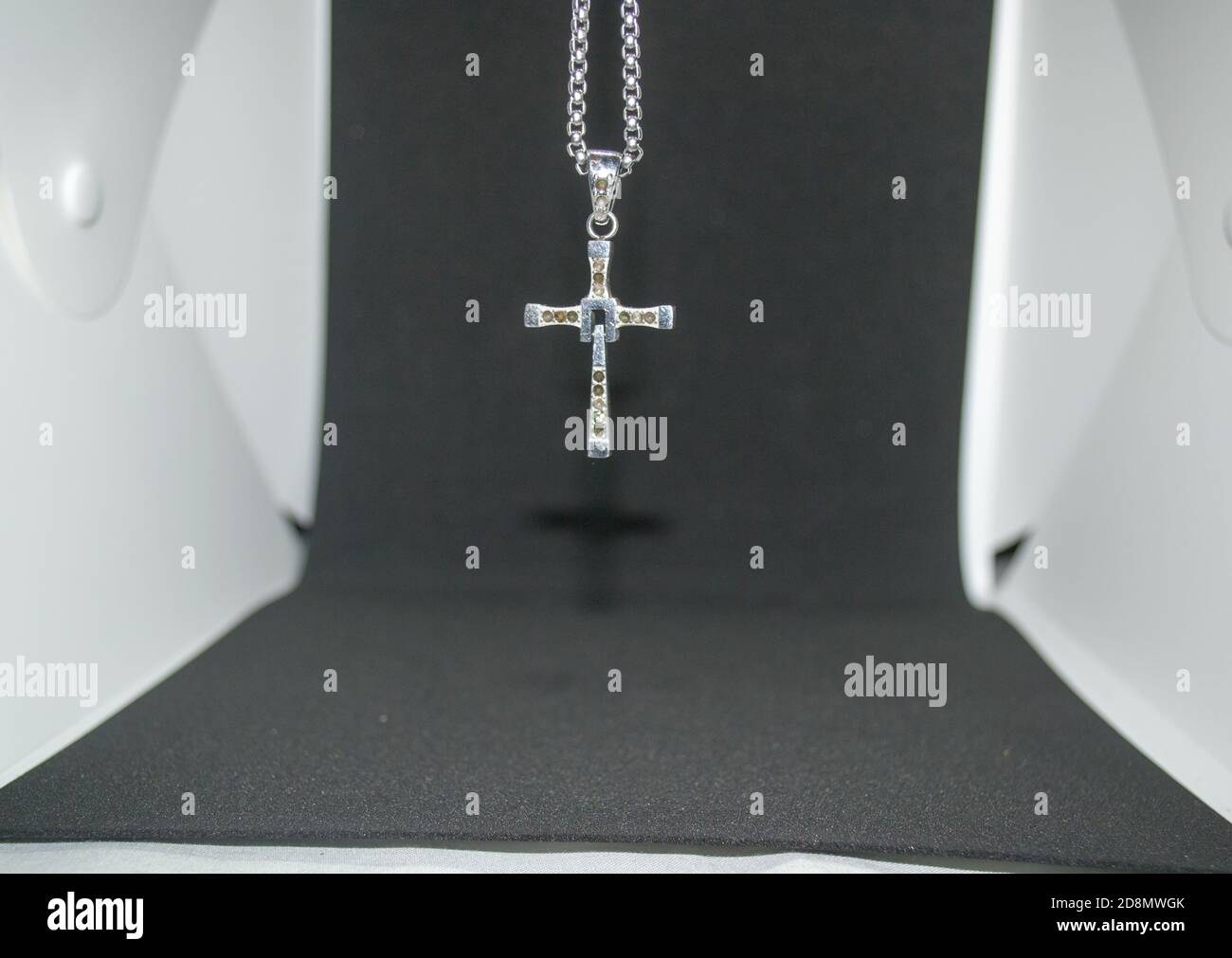 Immagine ravvicinata di una collana/pendente a croce cristiana in metallo argento o. collana/pendente in metallo-argento con crocifisso appeso su un bianco e nero sfondo Foto Stock