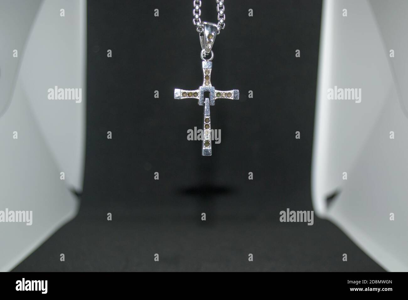 Immagine ravvicinata di una collana/pendente a croce cristiana in metallo argento o. collana/pendente in metallo-argento con crocifisso appeso su un bianco e nero sfondo Foto Stock
