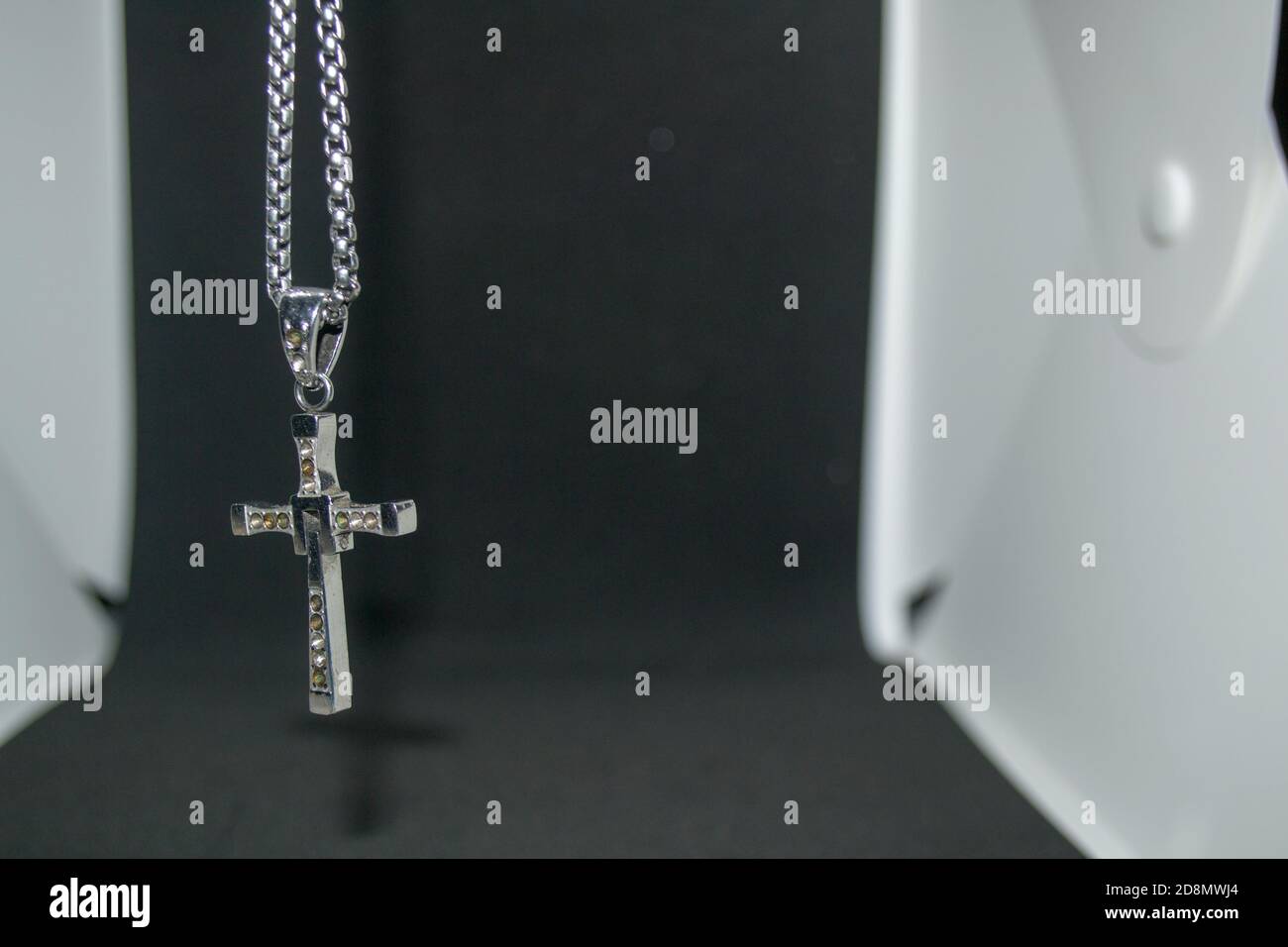 Immagine ravvicinata di una collana/pendente a croce cristiana in metallo argento o. collana/pendente in metallo-argento con crocifisso appeso su un bianco e nero sfondo Foto Stock