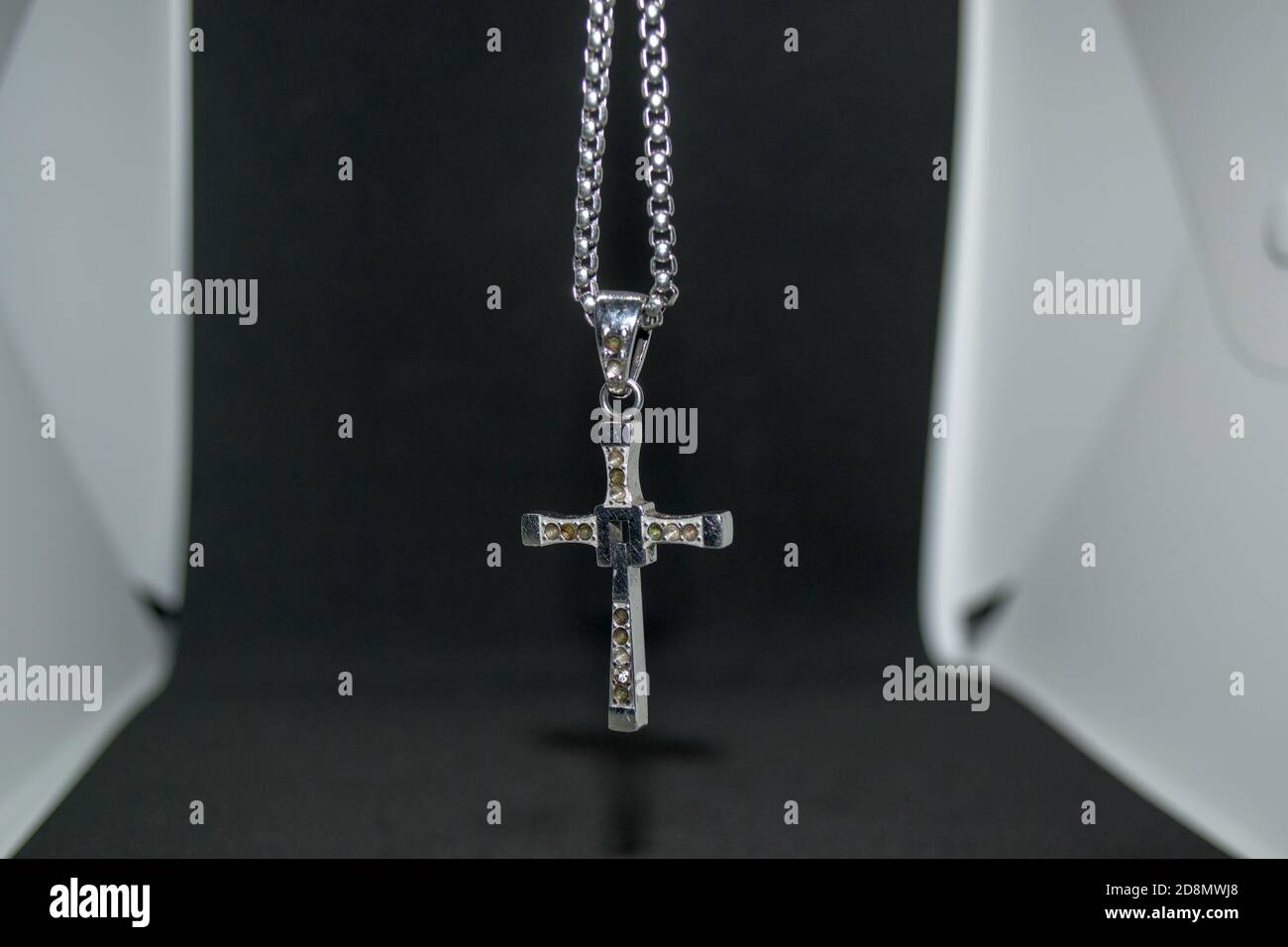 Immagine ravvicinata di una collana/pendente a croce cristiana in metallo argento o. collana/pendente in metallo-argento con crocifisso appeso su un bianco e nero sfondo Foto Stock