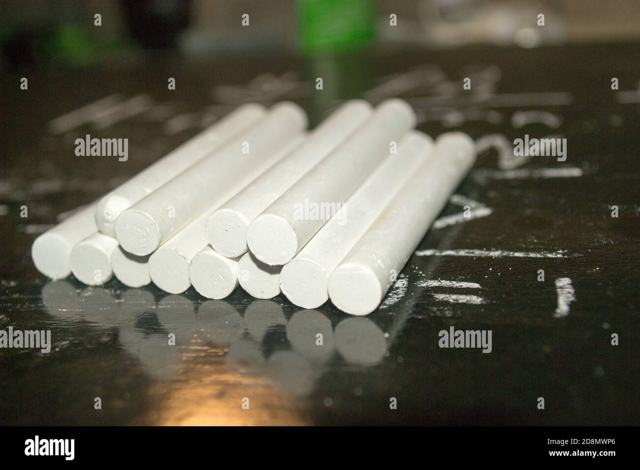 primo piano immagine di un mucchio di gessetti bianchi su una lavagna nera con equazioni matematiche scritte Foto Stock