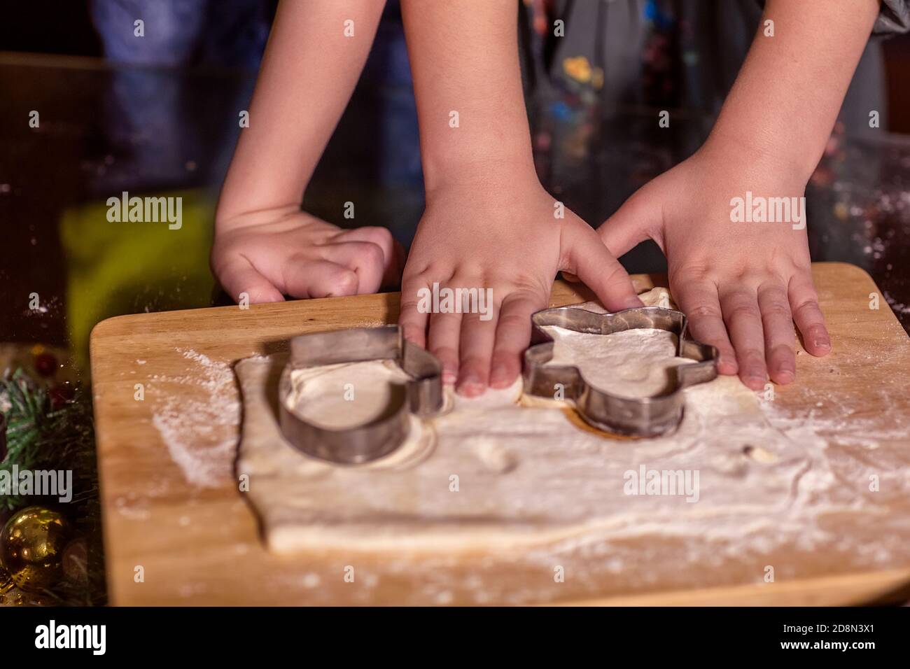I bambini tagliano i biscotti dalla pasta cruda con una taglierina per biscotti. Regalo di Natale per Babbo Natale. Primo piano delle mani. Messa a fuoco selettiva. Torte fatte in casa, Cristo Foto Stock