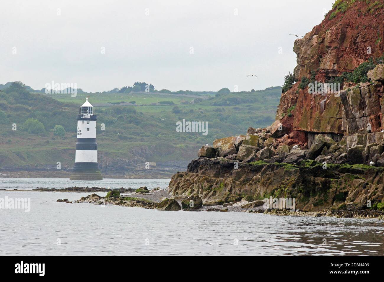 Faro di Penmon Point da Boat Off Puffin Island, Anglesey, Galles, Regno Unito Foto Stock
