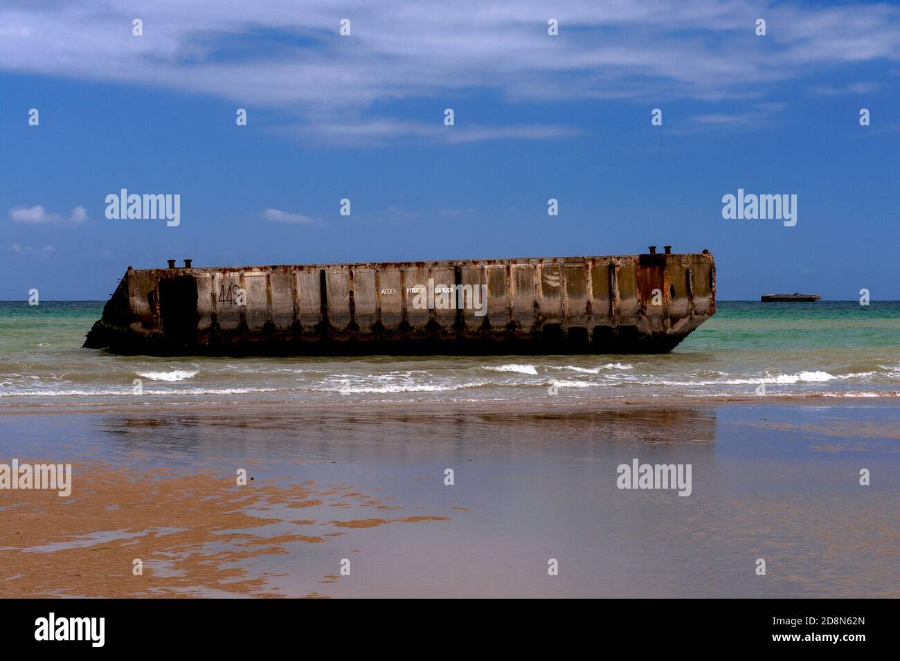 A bassa marea ad Arromanches, Calvados, Normandia, Francia, La gente può camminare fino al bordo dell’acqua sulla ‘Gold Beach’ della seconda guerra mondiale per raggiungere - ma non entrare - sezioni prefuse di calcestruzzo di Port Winston o Mulberry Harbour B. questo era il porto portatile prefabbricato di 600,000 tonnellate trainato attraverso la Manica, Assemblato in mare aperto e poi utilizzato per 10 mesi dopo l'operazione Overlord ‘D-Day’ invasione del 6 giugno 1944, per sbarcare 2.5 milioni di truppe britanniche e canadesi, mezzo milione di veicoli e quattro milioni di tonnellate di forniture. Foto Stock