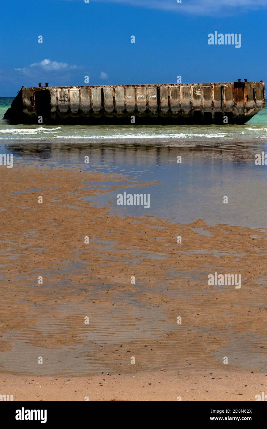 A bassa marea ad Arromanches, Calvados, Normandia, Francia, La gente può camminare fino al bordo dell’acqua sulla ‘Gold Beach’ della seconda guerra mondiale per raggiungere - ma non entrare - sezioni prefuse di calcestruzzo di Port Winston o Mulberry Harbour B. questo era il porto portatile prefabbricato di 600,000 tonnellate trainato attraverso la Manica, Assemblato in mare aperto e poi utilizzato per 10 mesi dopo l'operazione Overlord ‘D-Day’ invasione del 6 giugno 1944, per sbarcare 2.5 milioni di truppe britanniche e canadesi, mezzo milione di veicoli e quattro milioni di tonnellate di forniture. Foto Stock