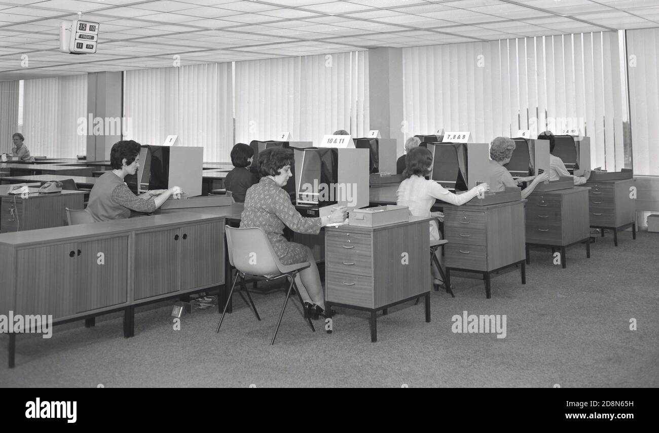Anni '60, storico, un certo numero di lavoratrici sedute a scrivanie che lavorano con grandi monitor 'Ginevra' su di loro in un ufficio open space, USA. Probabilmente gli schermi di visualizzazione sono lettori di microfiche utilizzati per la memorizzazione di dati e informazioni. Foto Stock