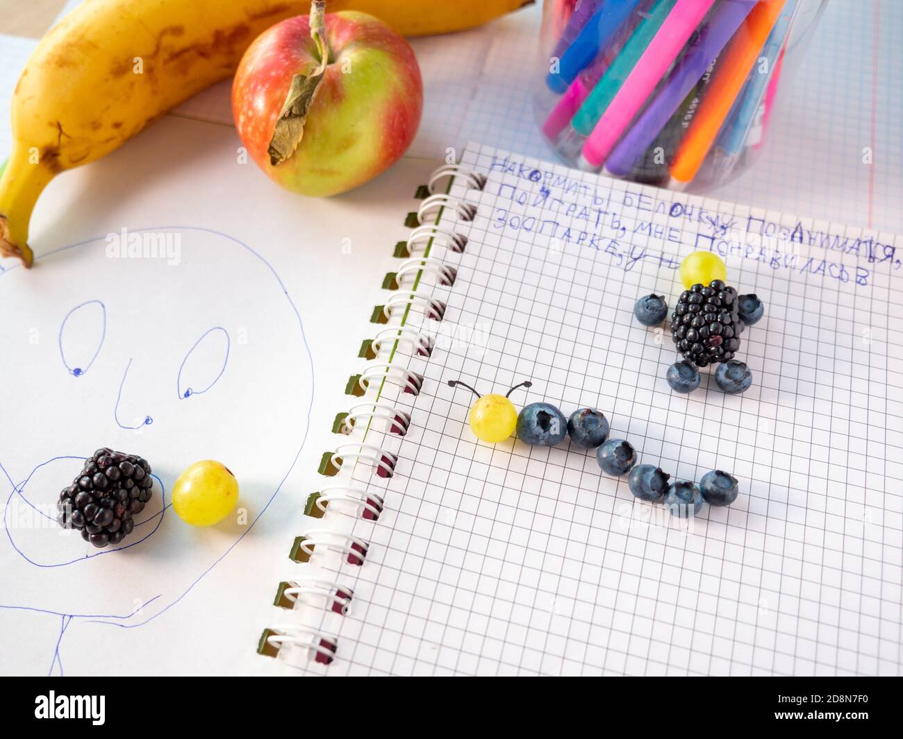 Bambini frutti di bosco sano mestiere. Fare e mangiare fresco. Semplice artigianato capretto: Blueberrycaterpille, mora e uomo mirtillo su una pagina di un notebook. Foto Stock