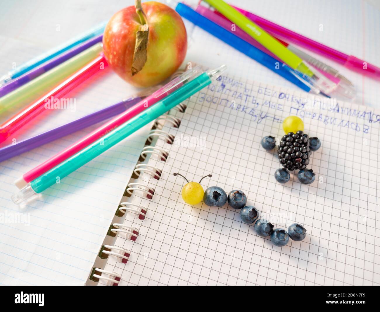 Semplice artigianato capretto: Mirtillo e uva caterpillar, mora e mirtillo uomo su una pagina di un taccuino grafico aperto anello-bound. Pausa sana. Foto Stock