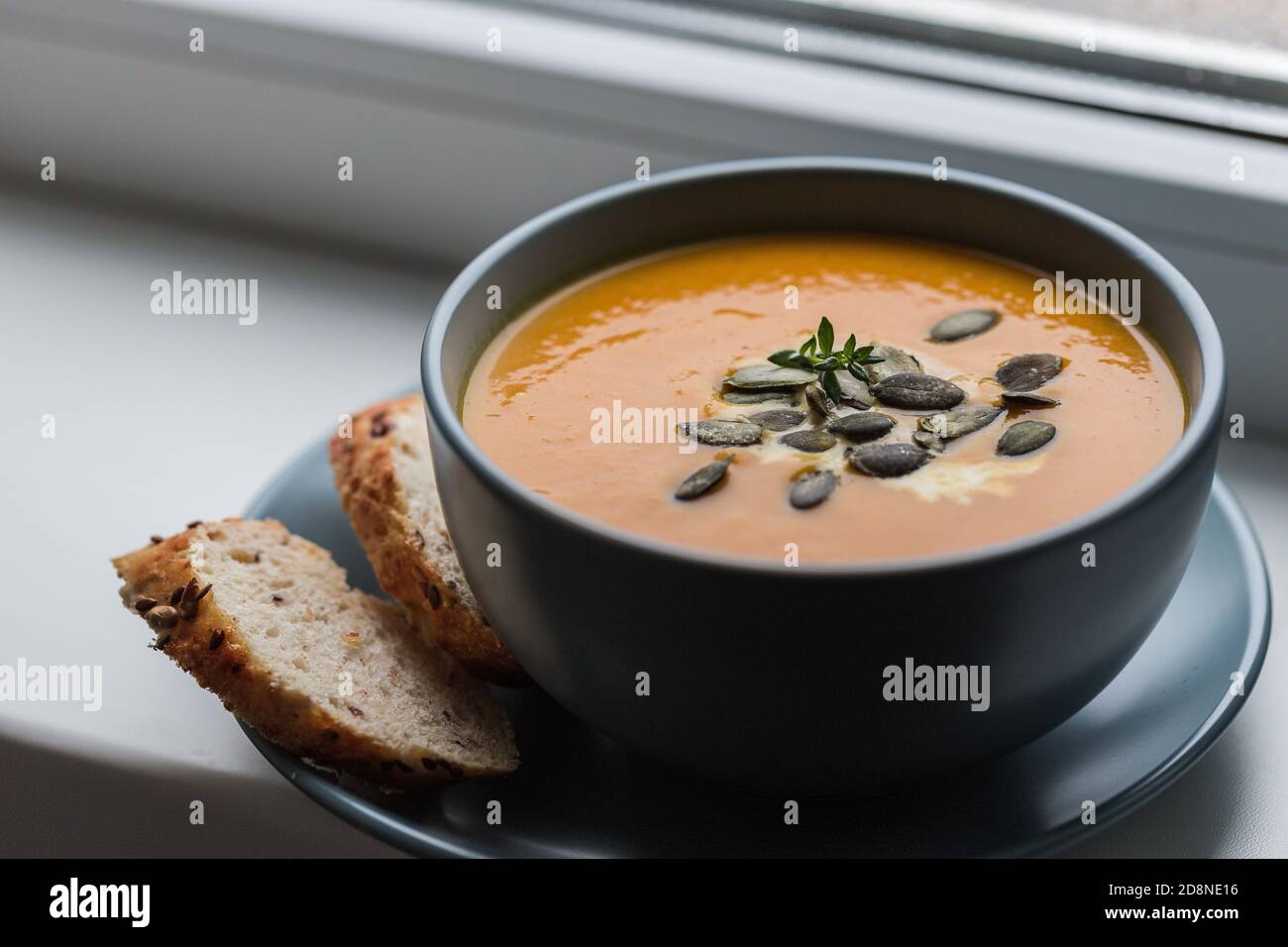 zuppa di crema di zucca e carote con semi di zucca e tostata pane Foto Stock
