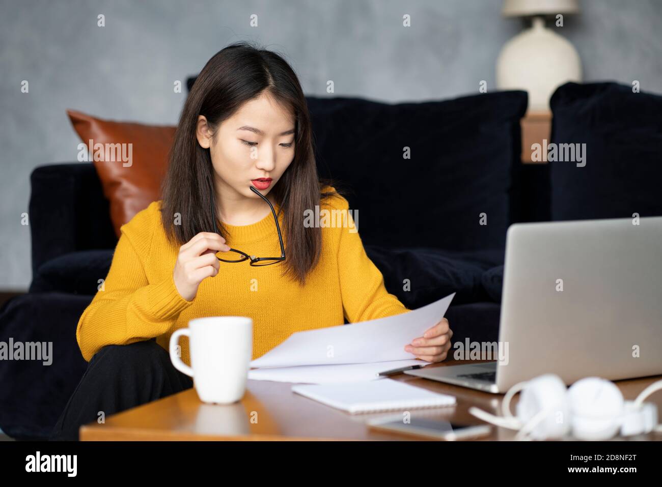 Donna asiatica che lavora a casa guardando i documenti. Bella ragazza giapponese freelance Foto Stock