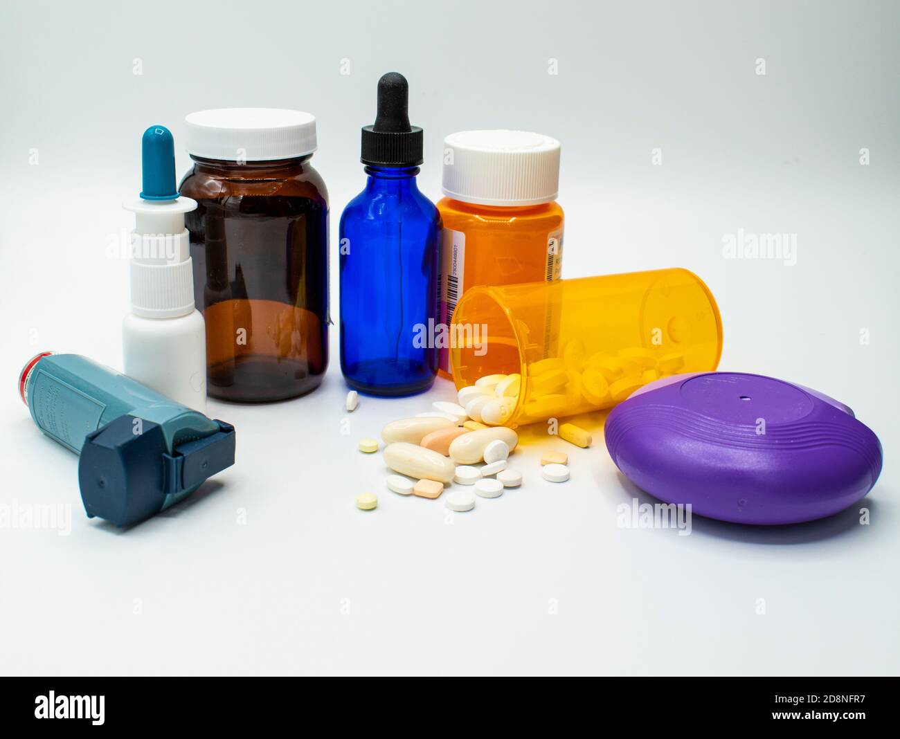 Vari flaconi di farmaco, inalatore, spray nasale, e gocce su uno sfondo bianco. Foto Stock