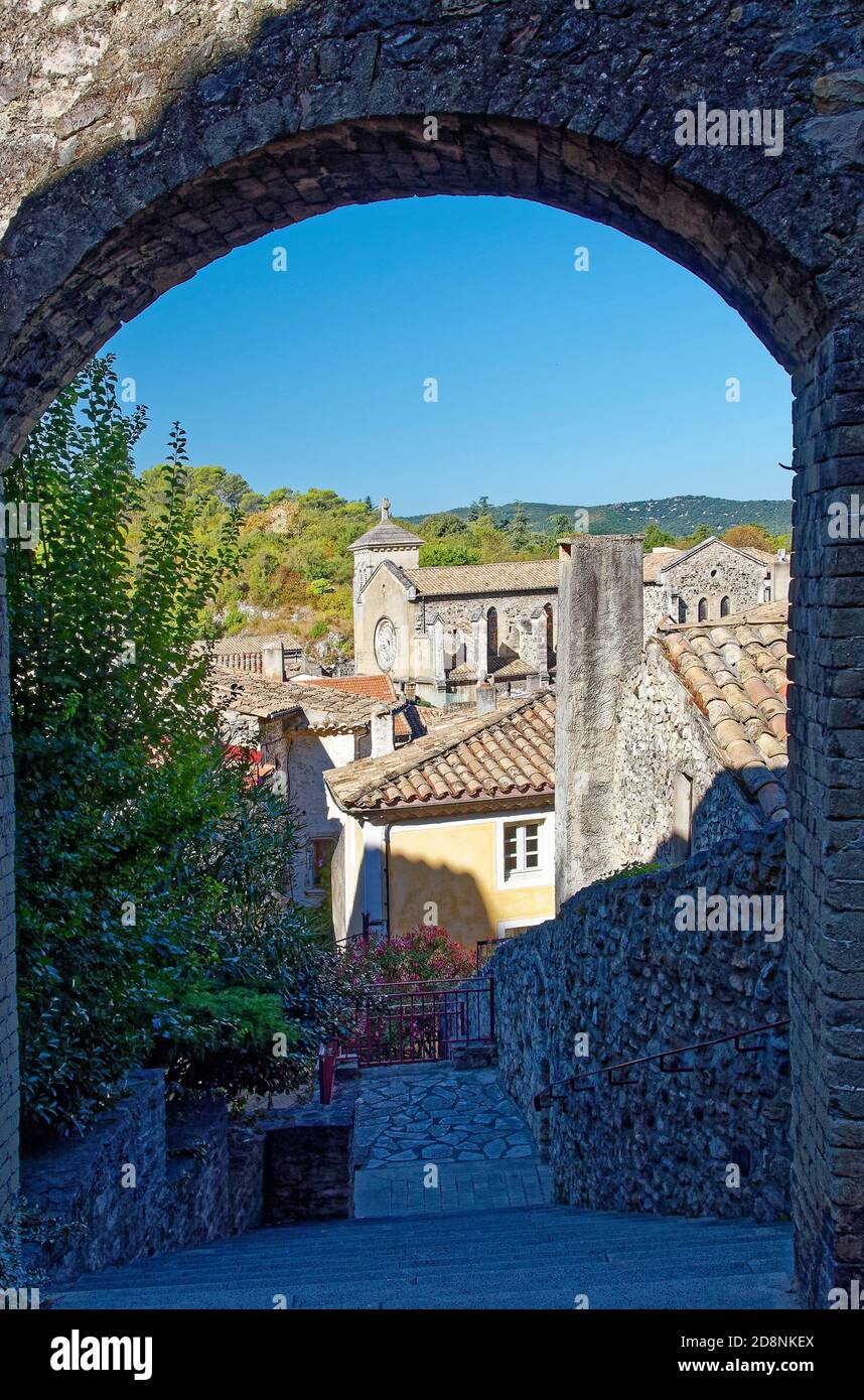 Vista sulla città attraverso archi in pietra, vecchi edifici, tetti in tegole, Chiesa, gradini ripidi, colline, Viviers Francia; estate, verticale Foto Stock