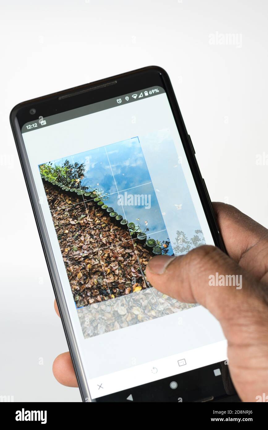 Persona che modifica una foto sullo smartphone per ritagliare un'immagine Foto Stock