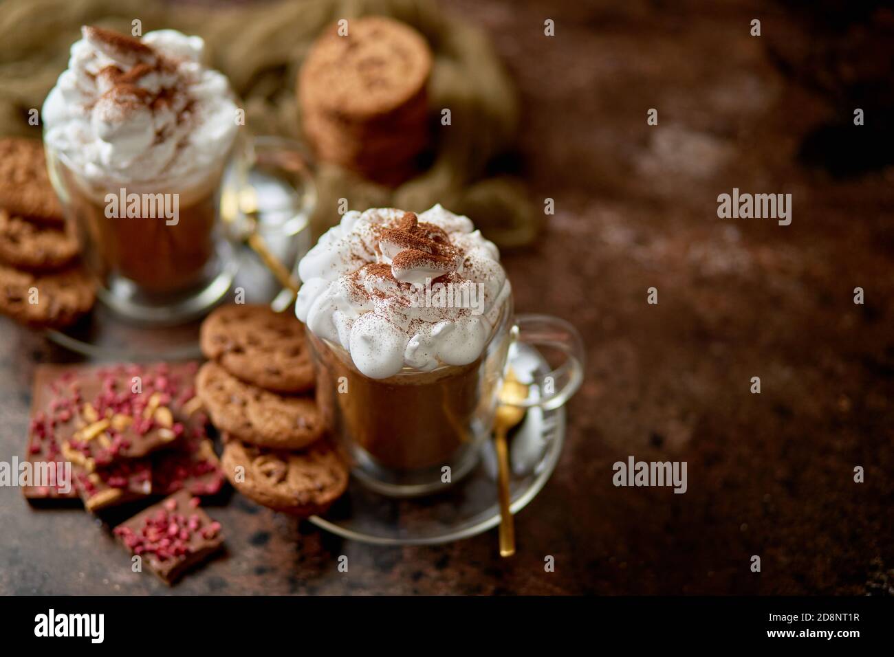 Due bicchieri alti con cioccolata calda, panna montata e polvere di cannella sopra Foto Stock