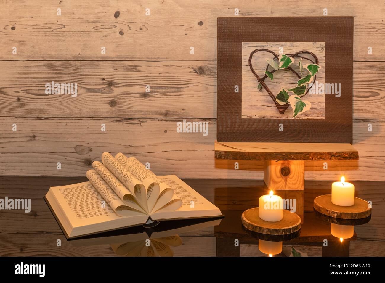 Libro ripiegato a forma di cuore su sfondo ligneo con riflessi. Foto Stock