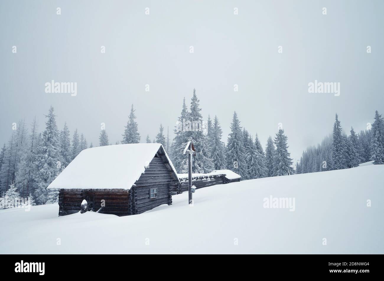 Paesaggio invernale con una valle di montagna. Una croce di legno con un crocifisso vicino alla capanna. Carpazi, Ucraina, Europa Foto Stock