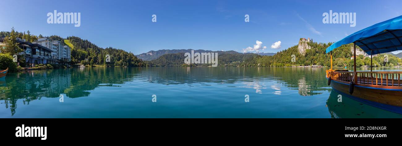 Una foto panoramica del Lago di Bled, che mostra una delle gondole (chiamato 'pletna'), il Castello di Bled e l'Isola del Lago di Bled. Foto Stock