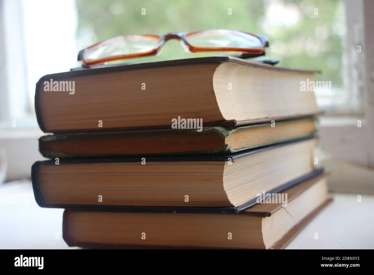 Quattro vecchi libri e occhiali vicino alla finestra. Concetto di educazione alla conoscenza Foto Stock