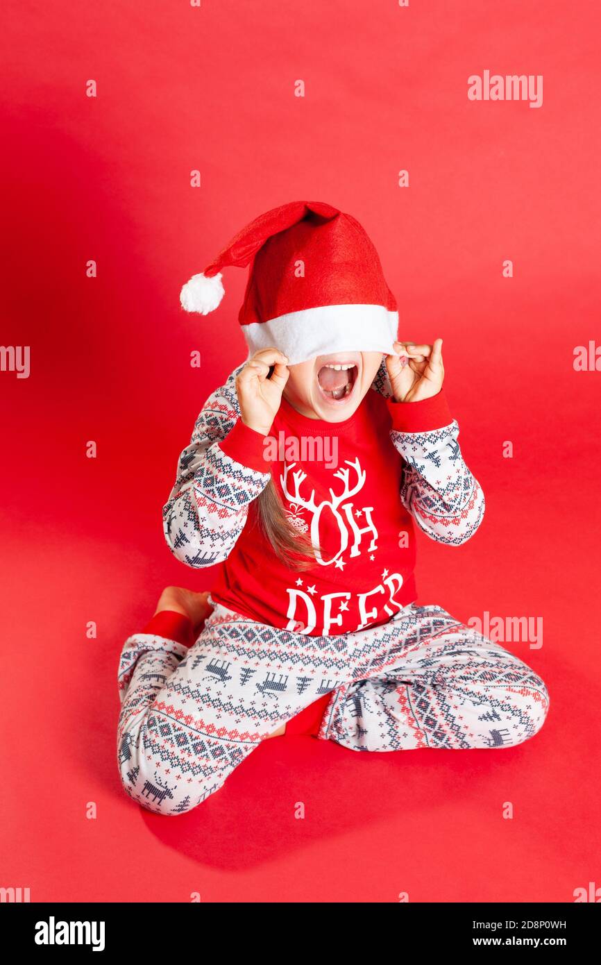 Una ragazza felice in pigiami rossi di Natale con pelli di renna Sotto un  cappello di Babbo Natale su sfondo rosso Foto stock - Alamy