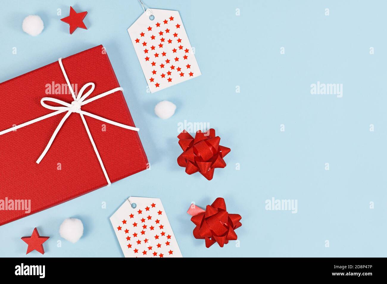 Piatto di Natale con scatole regalo rosse e robbons, labesl regalo e ornamento palla di neve su sfondo azzurro con spazio di copia sul lato Foto Stock